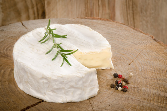 camembert on wood with rosemary and pepper