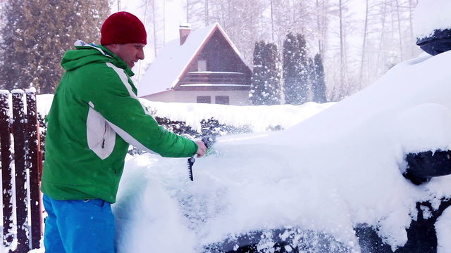 Man cleaning car after snow blizzard