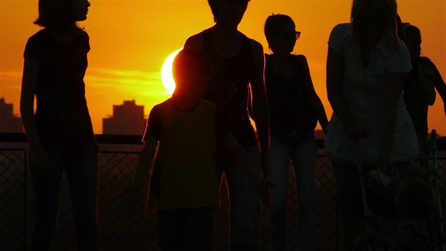 Silhouettes of people walking and enjoying beautiful sunset.