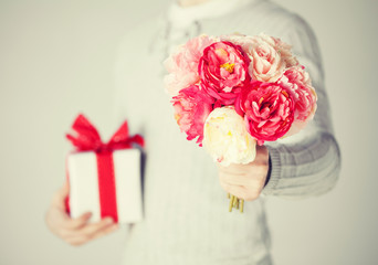 man holding bouquet of flowers and gift box