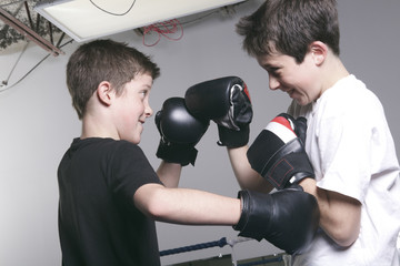 young boy with black boxing gloves fight with is brother