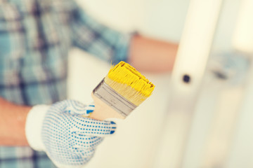 close up of male in gloves holding paintbrush