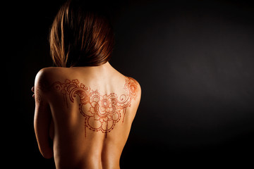 naked back of young girl with henna tattoo mehendi