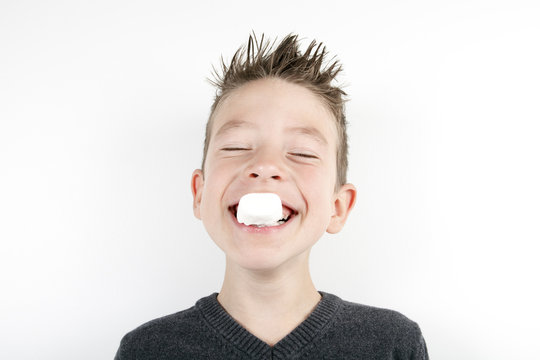 Portrait of cute joyful boy with a marshmallow