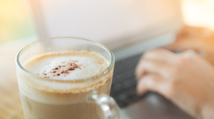 Closeup of coffee and  hand typing on laptop keyboard