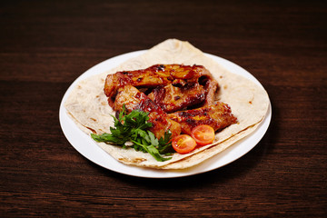 Plate with roasted pork ribs on wooden table