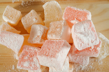 Turkish Delight in powdered sugar on wooden background close-up.