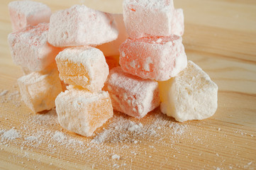 Turkish Delight in powdered sugar on wooden background close-up.