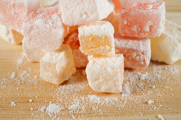 Turkish Delight in powdered sugar on wooden background close-up
