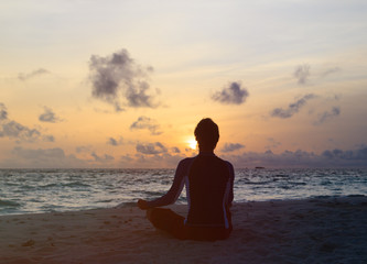 Silhouette of man meditating at sunset beach