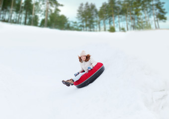 happy teenage girl sliding down on snow tube