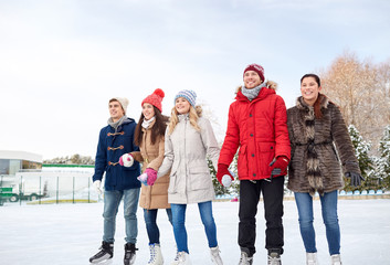 happy friends ice skating on rink outdoors