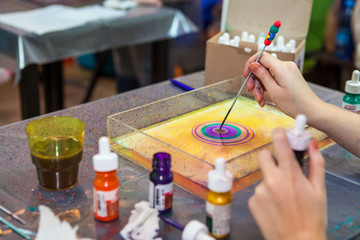 Man drawing with stick stained inks on water surface