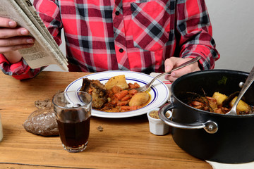 a man eat beef carrot and reading a newspaper