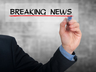 Businessman writing breaking news in the air. Grey background