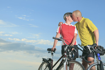 A senior man and a woman on bike at the sunset.