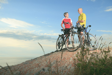 Fototapeta premium A senior man and a woman on bike at the sunset.