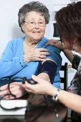 A girl help his mother taking her blood pressure