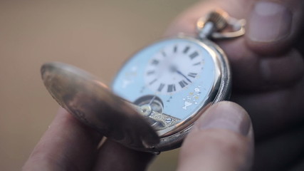 A man looks at the time of old pocket watches and closes them.