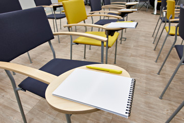 Chairs with notepads in empty classroom