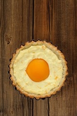 Peach tart with creamy filling on wooden background