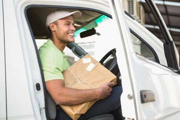 Smiling delivery driver in his van holding parcel