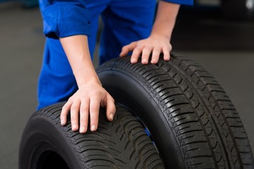 Obraz premium Mechanic rolling a tire wheel