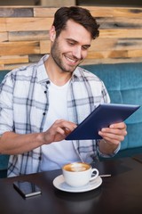 Young man having cup of coffee using tablet