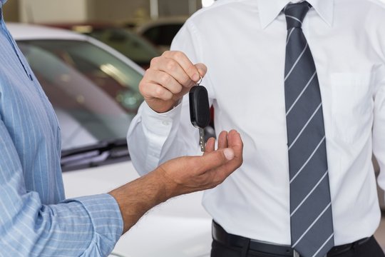 Businessman giving car key to customer