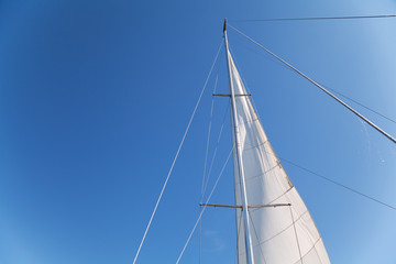 Mast and sail of yacht on blue sky background