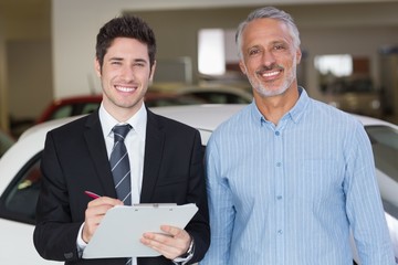 Smiling businessman writing on clipboard