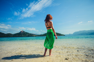 Woman wearing sarong on tropical beach - obrazy, fototapety, plakaty