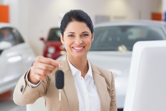 Smiling saleswoman giving a customer car key
