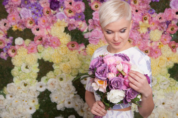 blond woman holding flowers, looking up, short haircut