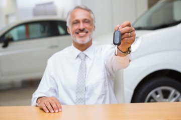 Smiling salesman giving a customer car keys