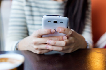 Young beautiful woman using her mobile phone in coffee.