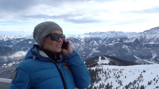 Attractive woman talking on cellphone in the mountains, Alps