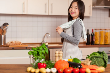 asian smiling woman standing in the kitchen with colorful ingred