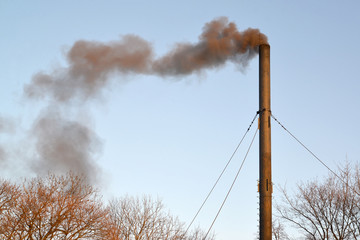 The black smoke from a pipe of a coal boiler room pollutes air.