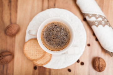 White cup of coffee, nuts, sugar on a wooden table.breakfast con