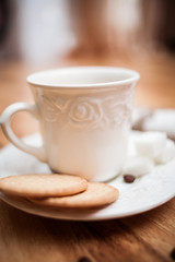 White cup of coffee, nuts, sugar on a wooden table.breakfast con