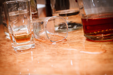 Glass, spilled whiskey and empty bottles on the bar.Alcoholism c