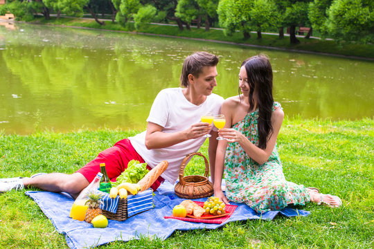 Young happy couple picnicking outdoors near the lake