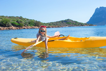 Little adorable happy girl kayaking in blue sea during summer