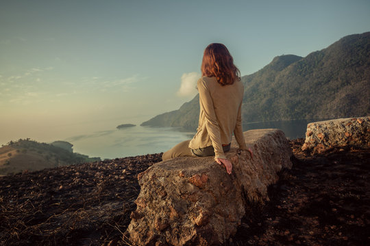 Woman sitting on unusual rock at sunrise