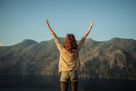 Woman raising her arms on top of mountain