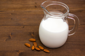 Almond milk in jug on wooden table