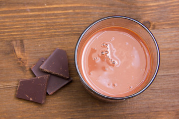 Glass with cocoa drink on wooden table seen from above