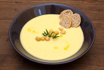 Cream of chickpeas and croutons on wooden table