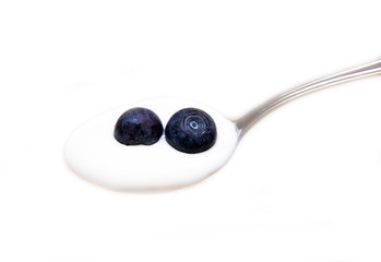 Spoon with yogurt and blueberries on white background